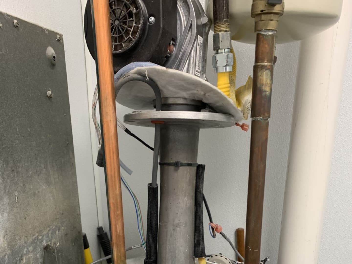 Close-up of a water heater burner assembly between copper and gas lines